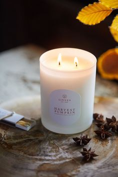 a white candle sitting on top of a wooden table next to an orange and some cinnamons