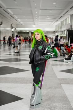 a woman with green hair standing on top of a pair of boots in an airport