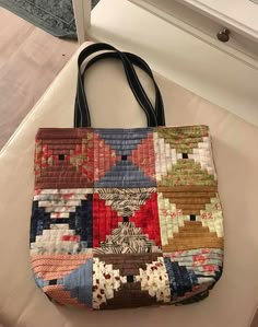 a multicolored handbag sitting on top of a white counter next to a mirror