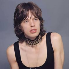 a woman wearing a black top with a necklace on it's neck and an ornate choker around her neck