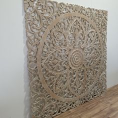 an intricately carved wall panel on the side of a white wall with wood flooring