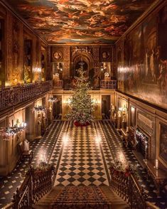 a christmas tree in the middle of a room with paintings on the walls and ceiling