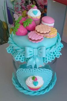 there is a blue cake with cupcakes and other items on top of it