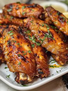 grilled chicken wings on a plate with lemon wedges and parsley garnish