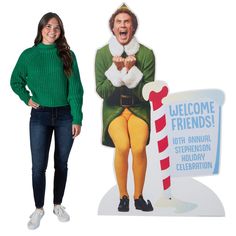 a woman standing in front of a welcome sign and a christmas card with an image of a man holding a candy cane