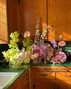 some flowers are sitting on a counter in a kitchen next to a sink and cabinets