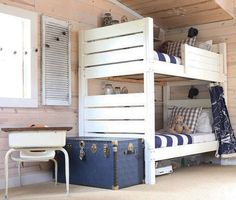 a bunk bed with two sets of drawers and a desk next to it in a room that has wood paneling on the walls