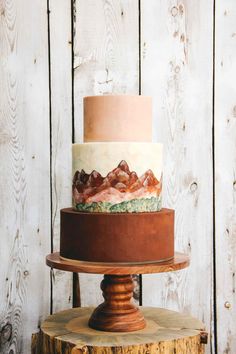 a three layer cake sitting on top of a wooden stand