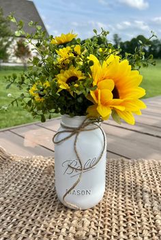 a mason jar filled with sunflowers on top of a table