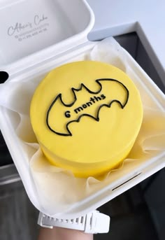 a yellow batman cake in a plastic container