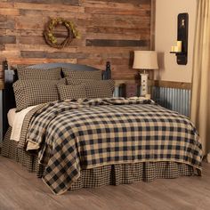 a bed with a plaid comforter and pillows in a room that has wood paneling on the wall