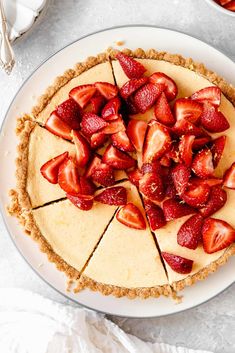 a cheesecake topped with sliced strawberries on a white plate