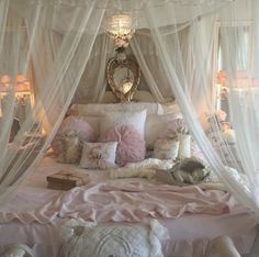 a canopy bed with pink and white pillows