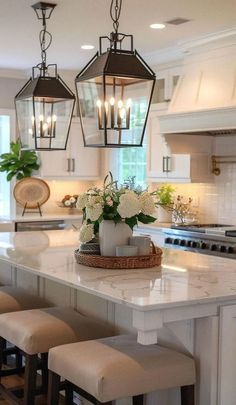 a kitchen island with stools and lights hanging from it's ceiling above it