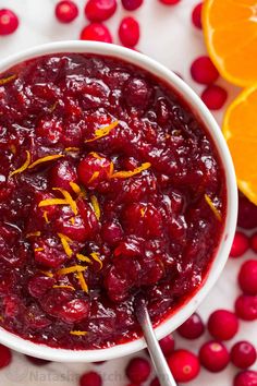 cranberry sauce with orange zest in a white bowl next to an orange slice