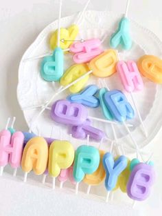 colorful birthday candles on a plate with the word happy spelled out