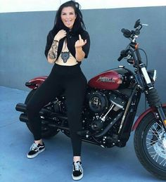 a woman sitting on top of a motorcycle giving the peace sign with her hand and thumbs up