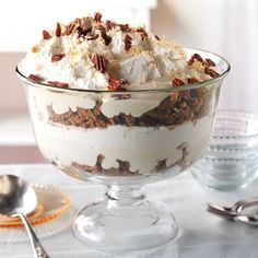 a dessert dish with pecans, whipped cream and walnuts on top is sitting on a table