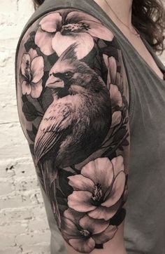 a woman's arm with flowers and a bird on the back of her shoulder