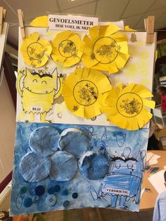 paper flowers are hanging on a clothesline in front of a child's artwork