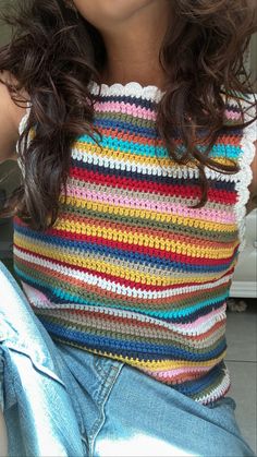 a close up of a person wearing glasses and a top with multicolored crochet