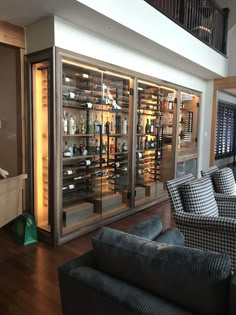 a living room filled with furniture and lots of wine bottles in the glass case doors