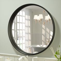 a round mirror hanging on the wall above a sink