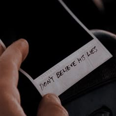 someone holding their cell phone with a note attached to it that says don't believe his lies