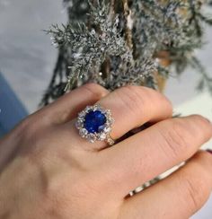 a woman's hand with a ring on it and a tree in the background