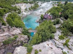 a river running through a lush green forest next to a rocky hillside covered in trees