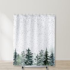 a shower curtain with trees and snow in the background on a wooden floor next to a white wall