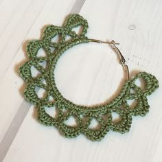 a green crochet hoop is shown on a white surface