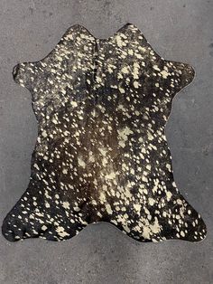 a black and white cowhide rug on the ground with spots of brown and white