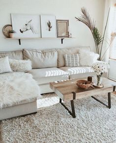 a living room with couches, coffee table and pictures on the wall above them