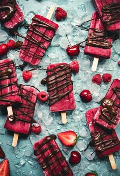 several popsicles with chocolate and strawberries on them sitting on top of ice cubes