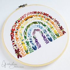 a cross stitch rainbow with flowers and butterflies on it's side is featured in this embroidery pattern