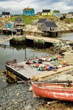 an old red boat sitting on top of a rocky shore