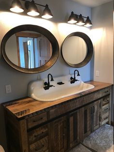 a bathroom sink with two mirrors above it and lights on either side of the sink