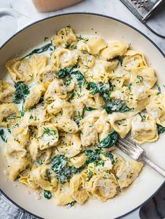 a skillet filled with pasta and spinach