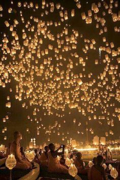 people are sitting on the ground and floating lanterns in the sky with words happy birthday