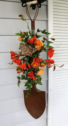 an orange flower arrangement hanging on the side of a house