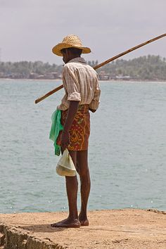 a man standing on the edge of a cliff with a fishing pole in his hand