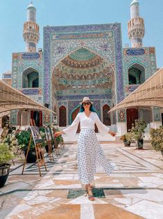 a woman standing in front of a blue and white building with an intricately decorated entrance