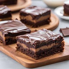 several pieces of chocolate cake sitting on top of a wooden cutting board