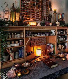 a table topped with lots of books and candles next to a shelf filled with jars