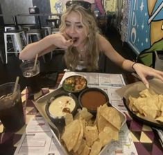 a woman sitting at a table with plates of food in front of her