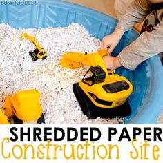 a child playing with construction toys in a blue plastic tub filled with shredded white paper