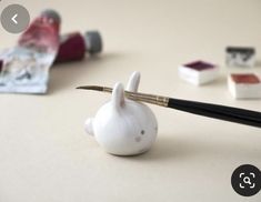 a pen sitting on top of a small white animal figurine next to other miniature items