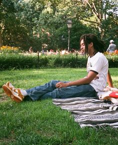 a man with dreadlocks sitting on a blanket in the grass