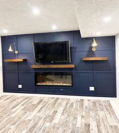 an empty living room with blue painted walls and wood flooring that has a fireplace in the center